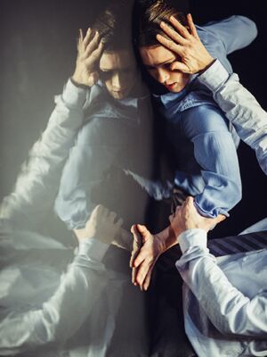 Two dancers: one leans against a glass wall while the other holds them.